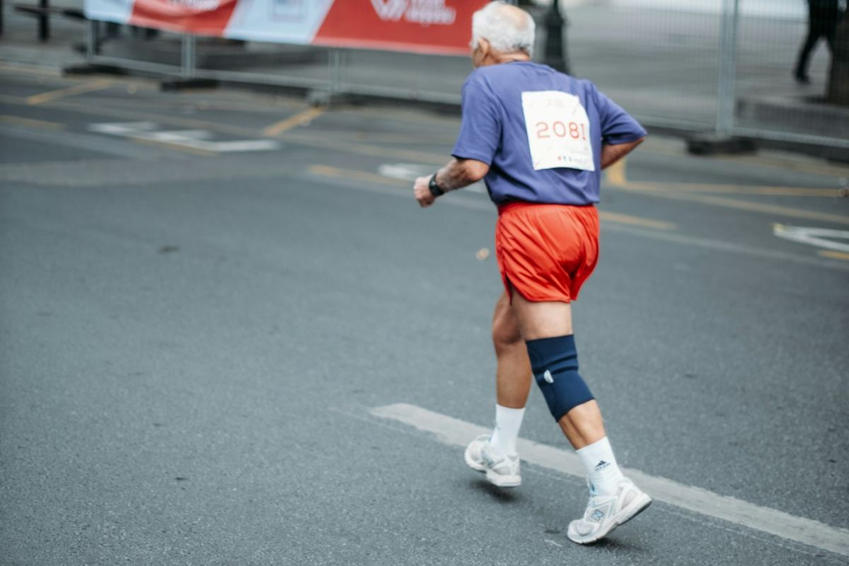 Äldre man som joggar på en asfaltsväg